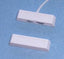 White Flair Electronics 1-inch gap surface mount alarm magnetic sensor with attached white cord on blue background
